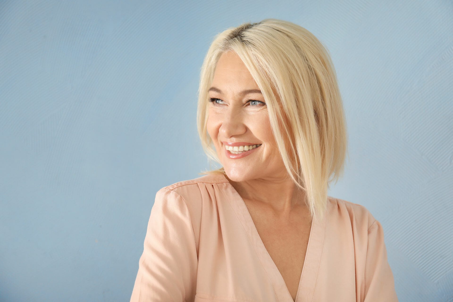 blonde-middle-aged-lady-smiling-on-blue-background